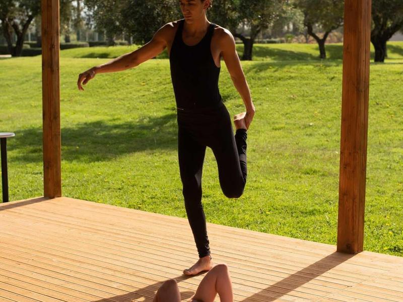 Žena cvičí venku, zatímco muž leží na terase.