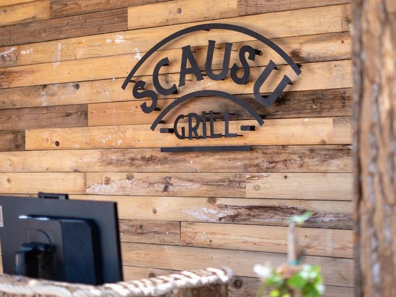 Rustikální dřevěná stěna s logem "Schlusty Grill" v restauraci.