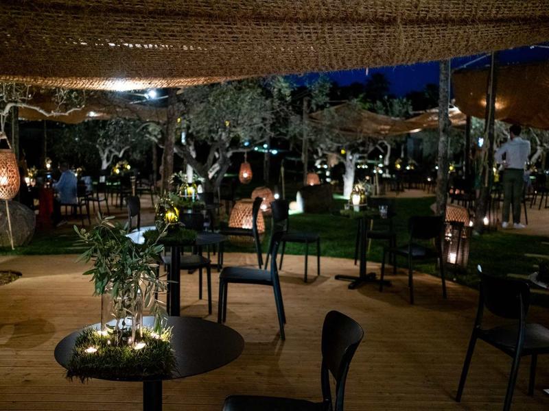 Příjemný venkovní bar s stoly, židlemi a náladovým osvětlením v noci