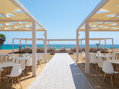 Open dining area with white chairs overlooking the sea and blue sky.