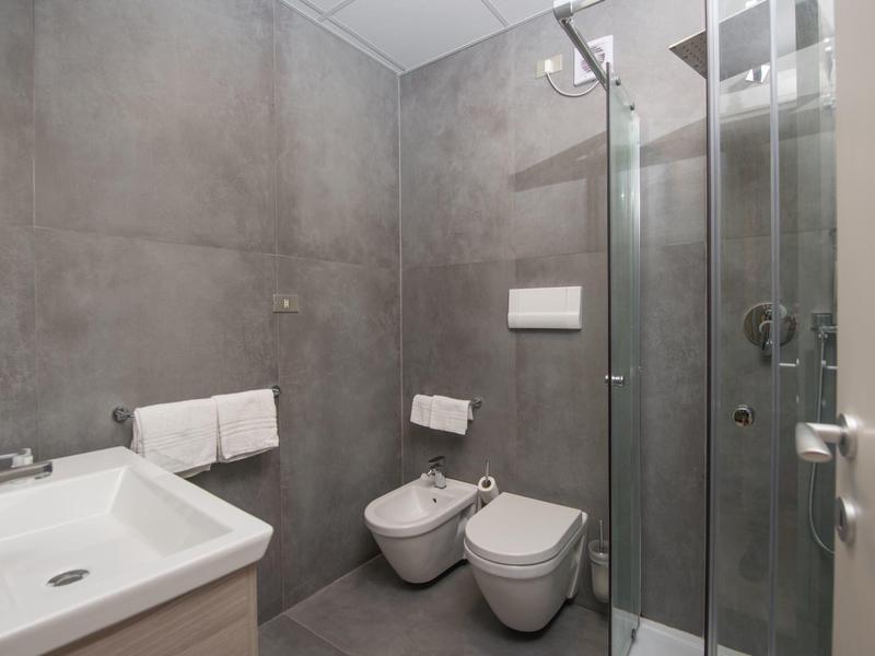 Modern bathroom featuring a shower, bidet, toilet, and sink in gray tones.