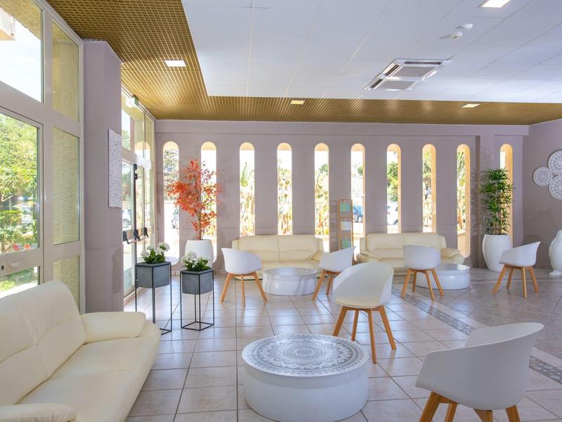 Bright, modern lounge area with white chairs and large windows in a hotel setting.