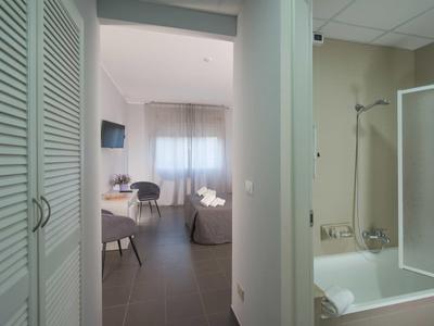 Widok na pokój hotelowy z wanną, telewizorem i częścią wypoczynkową z krzesłami i stołem.