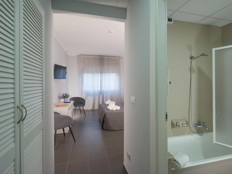 Widok na pokój hotelowy z wanną, telewizorem i częścią wypoczynkową z krzesłami i stołem.