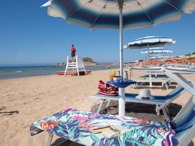 Sonnenschirme und Liegestühle am Sandstrand mit einem Rettungsschwimmer in der Nähe des Meeres.
