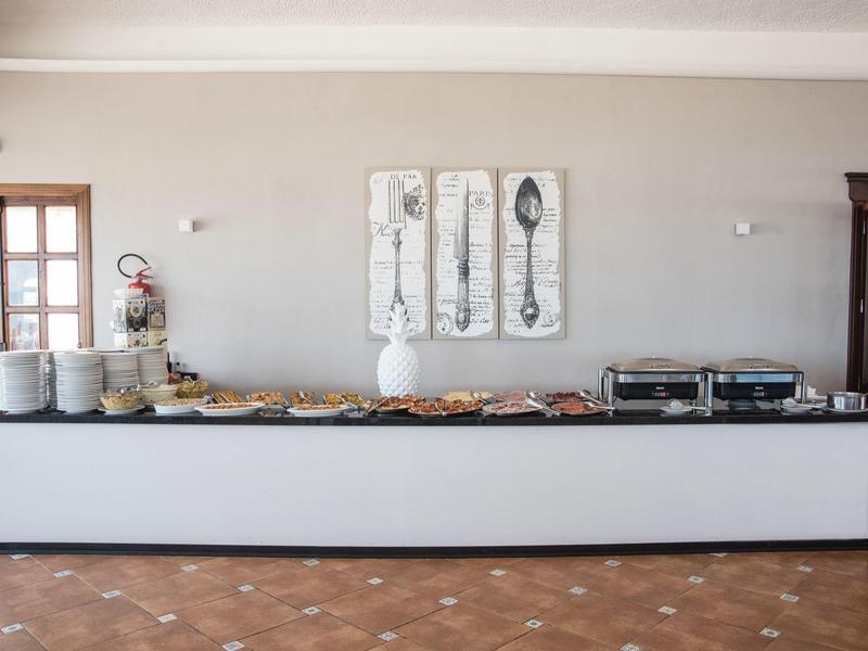 Buffet mit Gebäck und Getränken in einem hellen Raum mit rustikalem Boden.