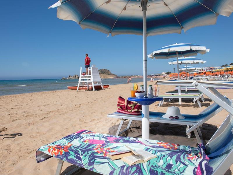 Sonnenschirme und Liegestühle am Sandstrand mit einem Rettungsschwimmer in der Nähe des Meeres.