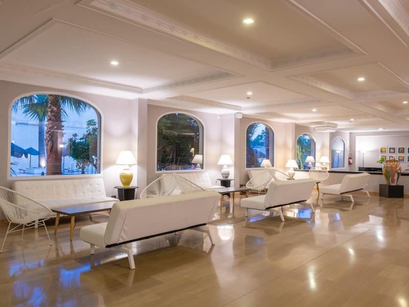 Heller, moderner Warteraum mit weißen Sesseln, großen Fenstern und glänzendem Fußboden.