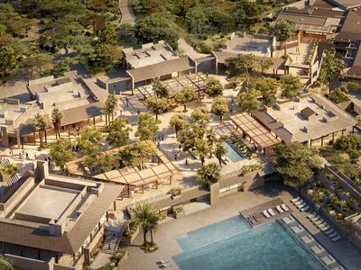 Letecký pohled na resort s několika budovami, palmami a velkým bazénem.