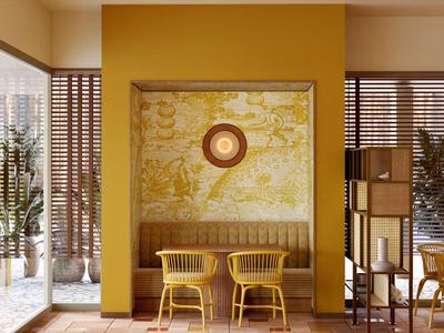 Moderní hotelová lounge se žlutou zdí, dvěma židlemi a velkými rostlinami.