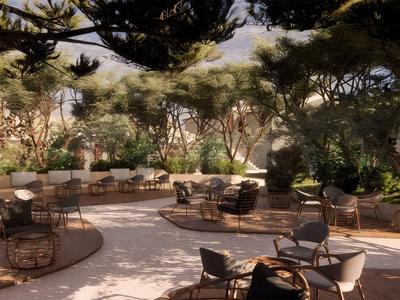 Slunná venkovní terasa s židlemi a stoly obklopená zelenými rostlinami a stromy.