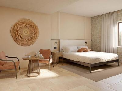 Světý hotelový pokoj s manželskou postelí, sezením a oknem s výhledem do zeleně.