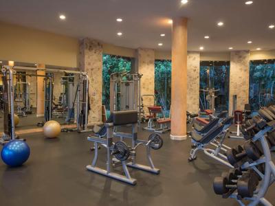 Fitnessstudio im Hotel mit verschiedenen Trainingsgeräten und großen Fenstern mit Blick ins Grüne