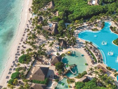 Luxuriöses Resort mit Pools neben einem weißen Sandstrand und türkisfarbenem Meer.