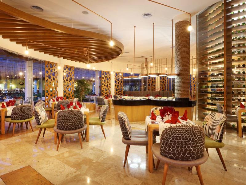 Moderner Restaurantbereich mit stilvollen Stühlen, Weinkühler und warmem Beleuchtungsdesign.