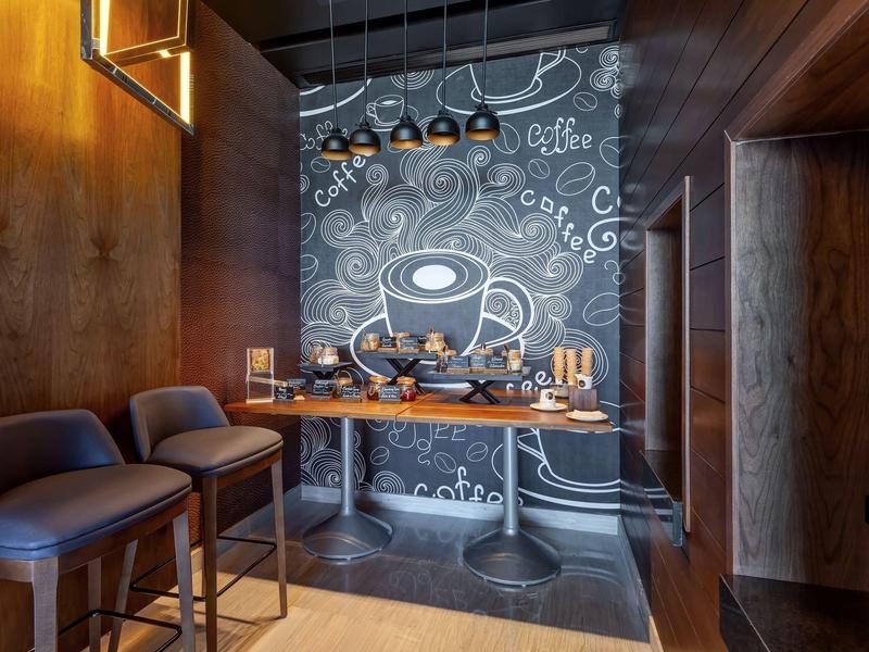 Gemütliche Kaffeebar mit Holzvertäfelung, hohen Sesseln, Holztisch und dekorativer Tafelwand.