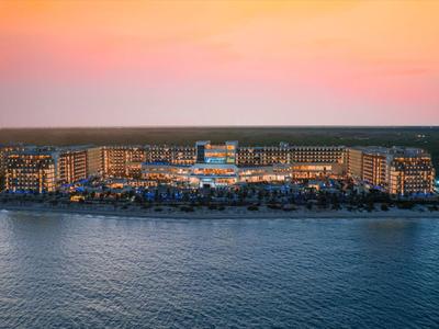 Licht beleuchtete Insel mit Gebäuden und Booten, ruhiges Meer, bunter Sonnenuntergangshimmel.