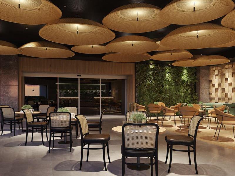 Moderner Gastronomiebereich mit runden Lampen, verschiedenen Stühlen und grüner Wanddeko.