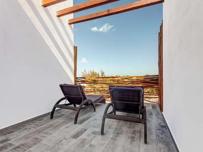 Zwei schwarze Liegestühle auf grauer Terrasse mit Holzbalken und Blick auf blauen Himmel.