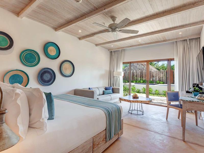 Hell eingerichtetes Schlafzimmer mit Holzbalkendecke, großen Fenstern und dekorativen Wandkörben.