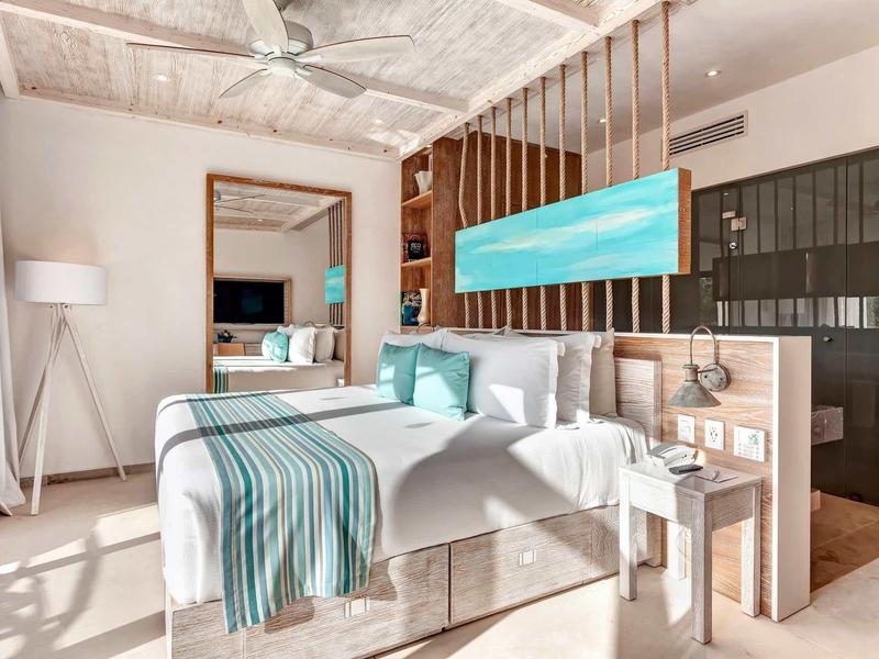 Helles Schlafzimmer mit Doppelbett, großem Spiegel, Holzdecke und modernem, blau-weißem Dekor.