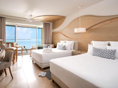 Modern eingerichtetes Hotelzimmer mit zwei Betten und Blick aufs Meer.