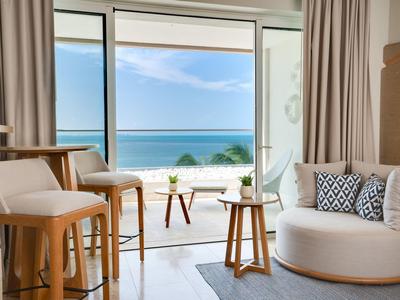 Moderner Hotelraum mit Sitzgelegenheiten und Meerblick durch große Fenster.