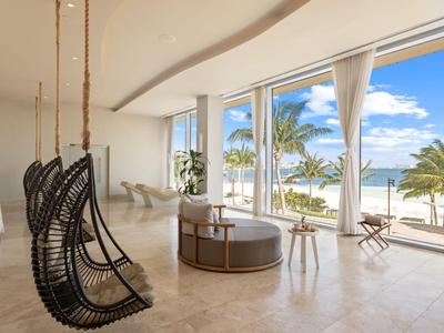 Moderne Hotellobby mit Schaukelsesseln und großem Meerblick durch raumhohe Fenster.