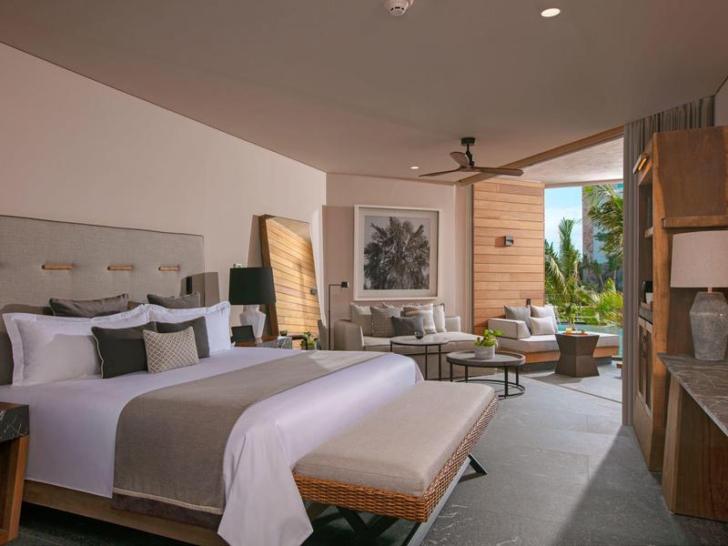 Modern eingerichtetes Schlafzimmer mit großem Bett, Sitzbank, Sofas und Balkon mit Pflanzen.