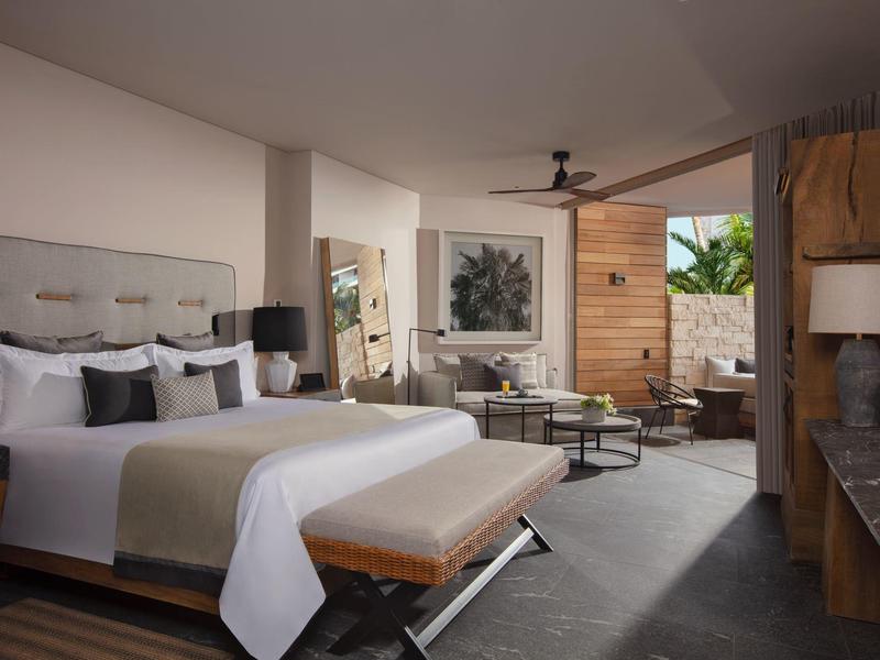 Helles modernes Schlafzimmer mit Doppelbett, Sitzbank, Sofa und Terrasse mit Holzverkleidung.