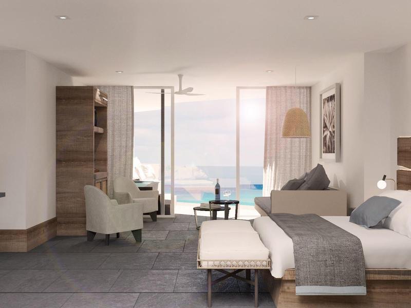 Helles Hotelzimmer mit Doppelbett, Sofa, Sesseln und großem Fenster mit Meerblick.