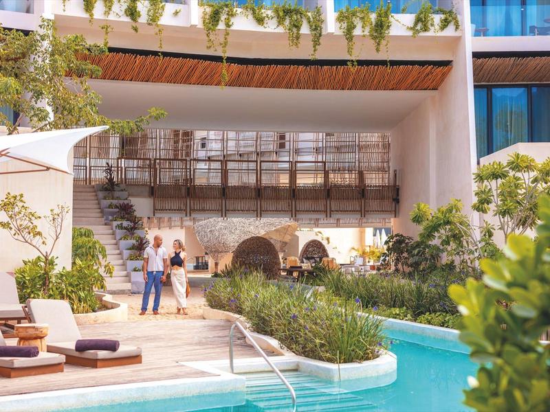 Nowoczesny basen hotelowy z leżakami i roślinami.