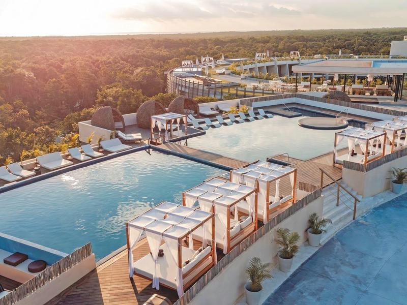 Duży basen infinity z tarasem słonecznym i leżakami w tropikalnym ośrodku.