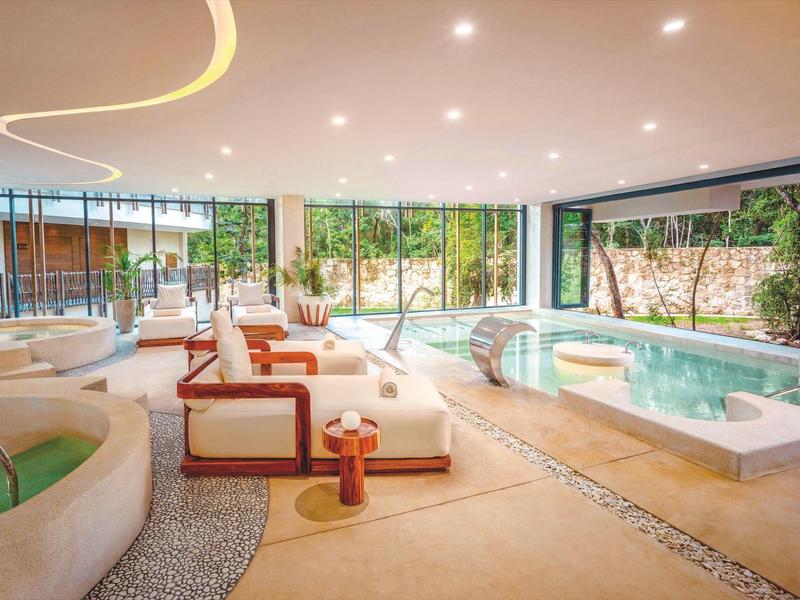 Nowoczesna strefa spa z basenami i wygodnymi miejscami do siedzenia w jasnym pomieszczeniu.