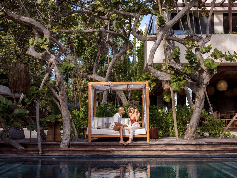 Zrelaksowana para na wiszącym łóżku przy basenie z tropikalnym tłem w ośrodku.