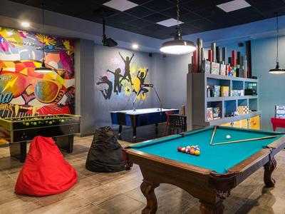 Freizeitraum mit Billardtisch, Tischfußball, Dartscheibe und Sitzsäcken in einem modernen Ambiente.