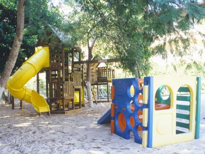 Aire de jeux avec toboggan et structure d'escalade sous des arbres dans une station de vacances