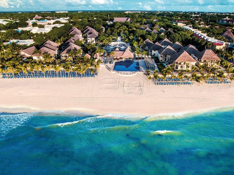 Complexe de luxe en bord de mer avec plage de sable blanc et eau turquoise claire.