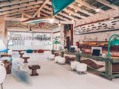 Área de salón de hotel luminosa con vigas de madera, bar y asientos cómodos.