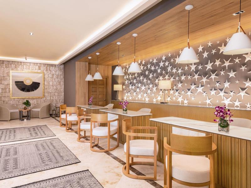 Moderner Empfangsbereich mit Holztheke, weißen Stühlen, Stern-Wanddekor und gemütlicher Beleuchtung.