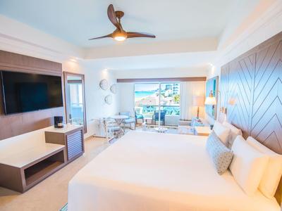 Habitación de hotel luminosa con cama grande, decoración moderna y balcón con vista al mar.