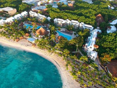 Luftaufnahme eines Hotelresorts mit Pool, Palmen und Strand an kristallklarem Wasser.
