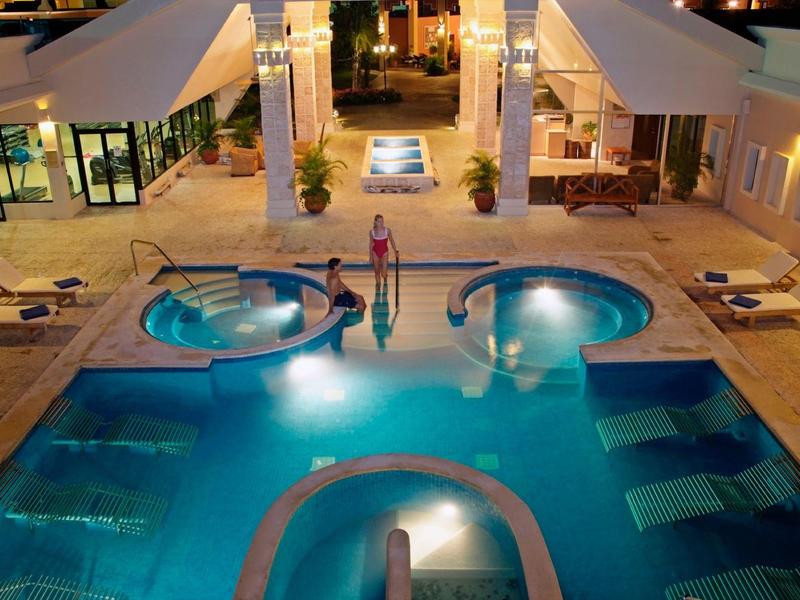 Piscina dell'hotel illuminata con aree idromassaggio integrate e sdraio di notte