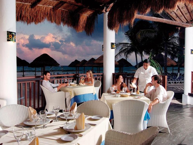 Cena all'aperto con vista mare, ospiti e personale in resort tropicale