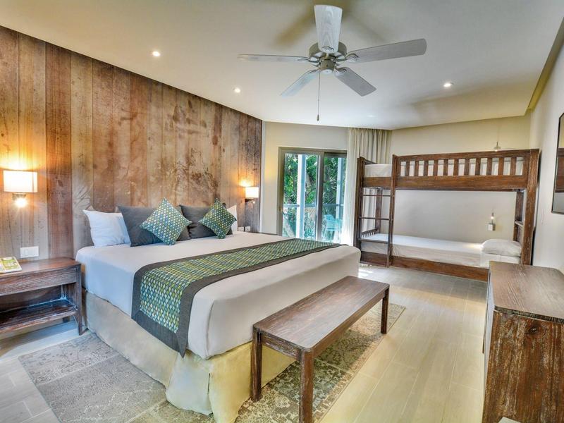 Camera moderna con letto matrimoniale, letto a castello e accesso al giardino.