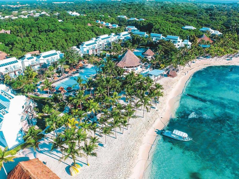 Vista aerea di un resort sulla spiaggia con acqua limpida e palme rigogliose