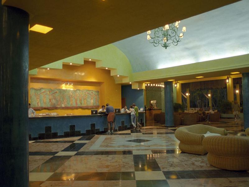 Spaziosa hall d'hotel con pavimento in marmo, aree salotto e illuminazione moderna.