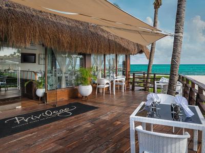 Hotel terrace with tables, chairs, and ocean view under clear sky.