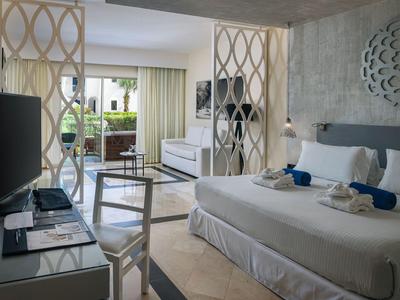 Modern hotel room with double bed, partition, and seating area with balcony access.
