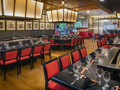 Modern restaurant with red chairs and elegantly set tables.